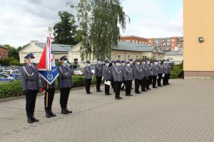 policjanci wciągają na maszt flagę państwową